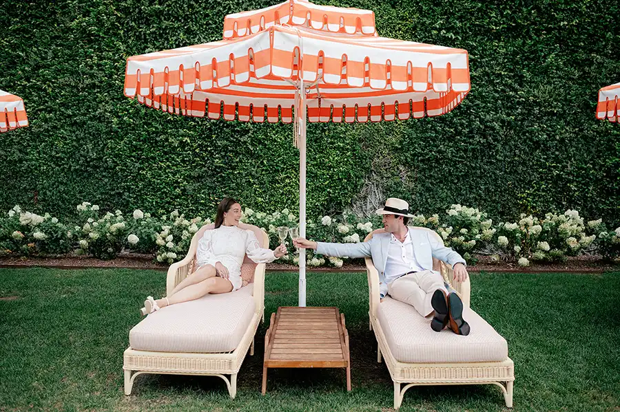 Couple relaxing under a striped orange umbrella during a stylish pre-wedding moment on Lake Como.