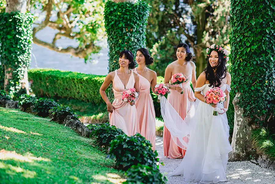 Bride with bridesmaids walking through the gardens of a Lake Como villa before the ceremony.