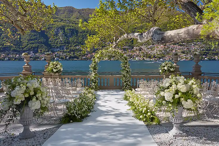 Outdoor wedding ceremony at Mandarin Oriental on Lake Como with white floral arch and lake view.