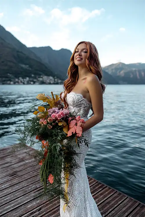 Bride portrait on a wooden pier on Lake Como holding a floral bouquet during a luxury wedding in Italy.