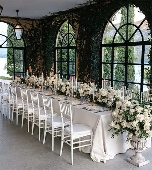 Elegant wedding dinner table at Villa del Balbianello on Lake Como with white floral arrangements.