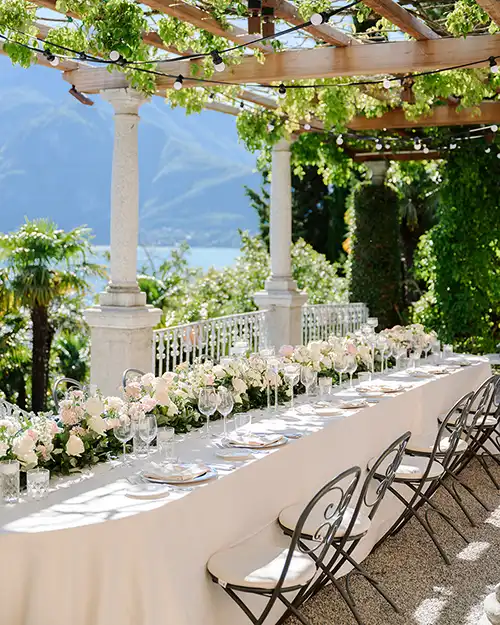 Elegant wedding table setup at Villa dei Cipressi on Lake Como under a pergola with lake view.
