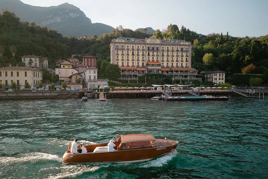 Wooden boat crossing Lake Como in front of Grand Hotel Tremezzo during a luxury wedding weekend in Italy.