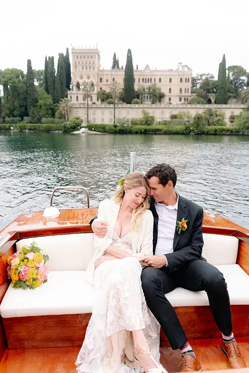 Bride and groom on a classic wooden boat in front of Isola del Garda during a wedding on Lake Garda