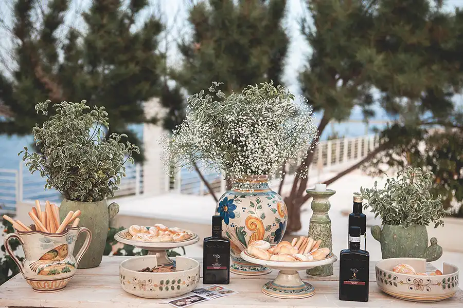 Sicilian wedding welcome table with ceramic vases, flowers, olive oil and traditional treats