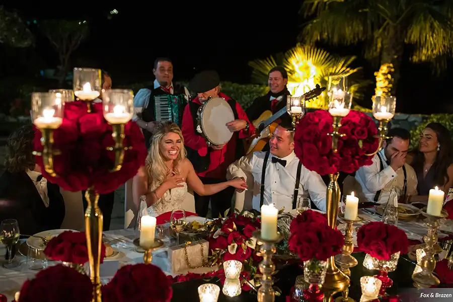Bride and groom during a wedding dinner in Sicily with live musicians, candles and red decor