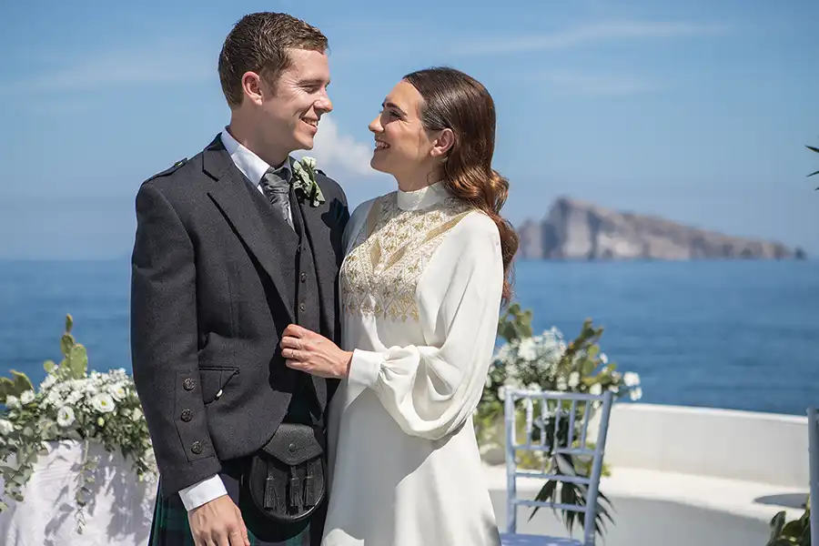 Couple in formal attire with sea view and island in the background during a wedding in Sicily