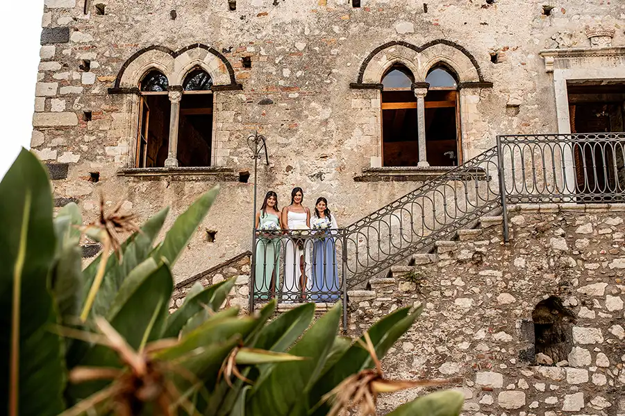 Bridesmaids standing on a stone staircase in front of a historic building during a wedding in Sicily