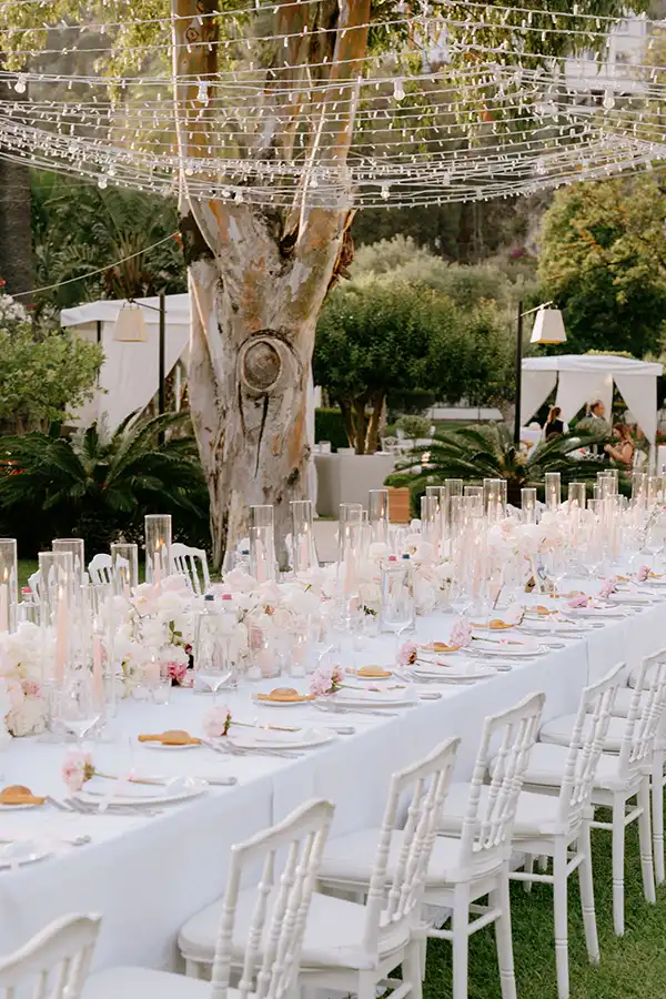 Elegant outdoor wedding reception in Sicily with long table, white flowers and garden lights