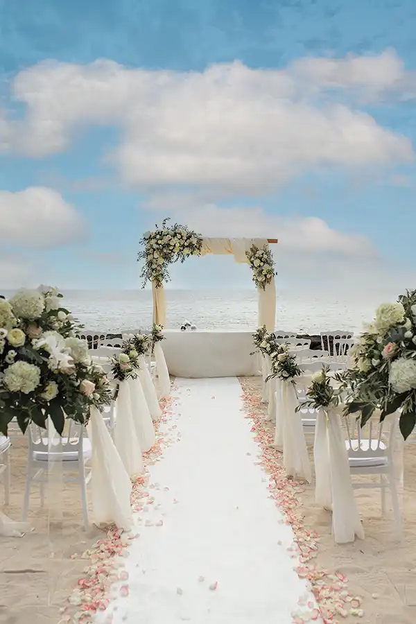 Seaside wedding ceremony setup in Sicily with white flowers, petals and ocean view
