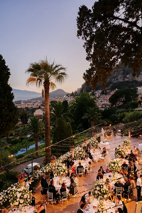 Romantic outdoor wedding reception in Taormina at sunset with floral decor and string lights