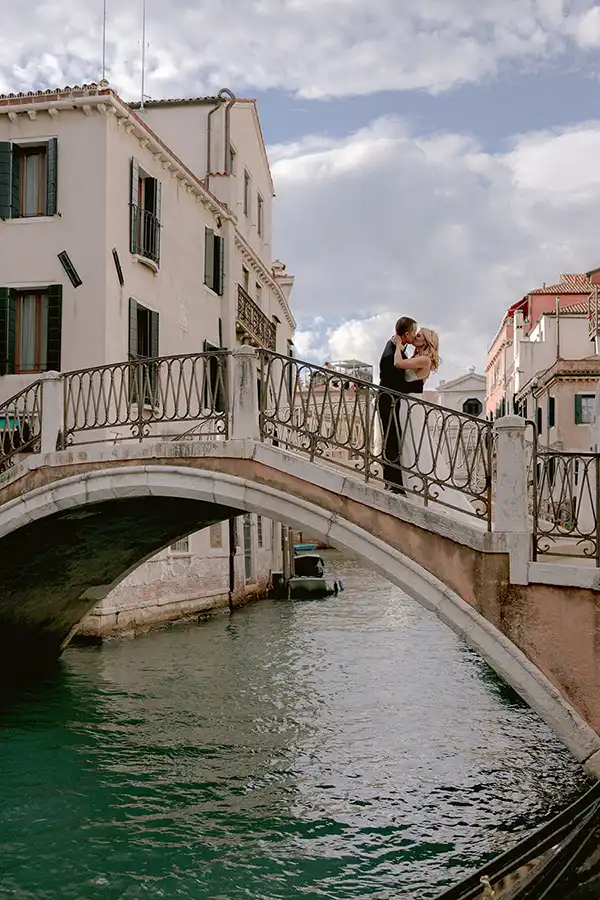 Bride and groom kissing on a small bridge over a canal during a wedding in Venice