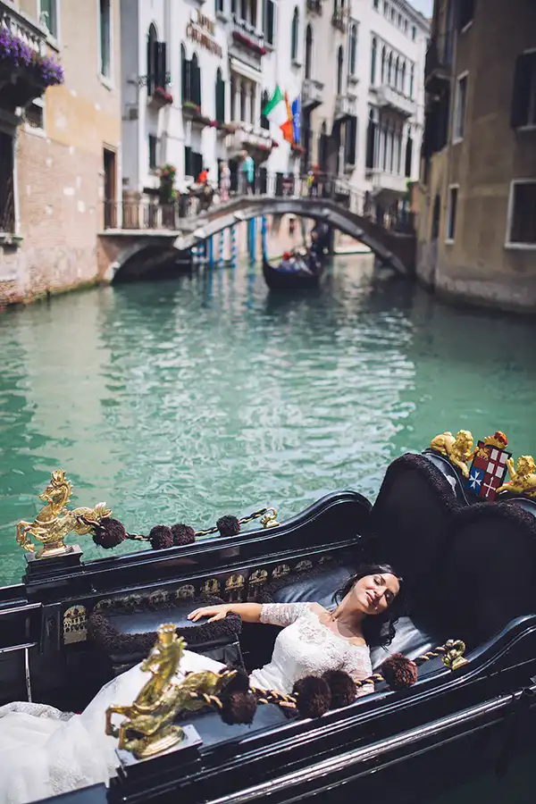 Bride relaxing in a gondola on a canal during a wedding in Venice