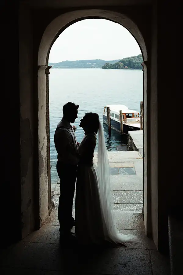 Bride and groom silhouetted in an archway on San Giulio Island overlooking Lake Orta