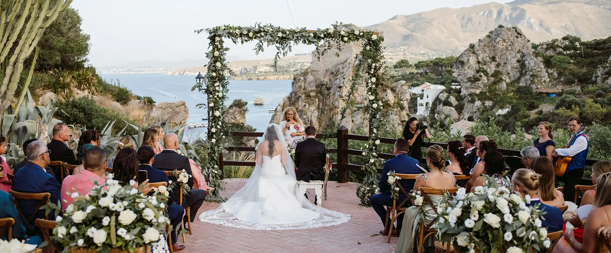 Outdoor wedding ceremony overlooking the Sicilian coast in Italy